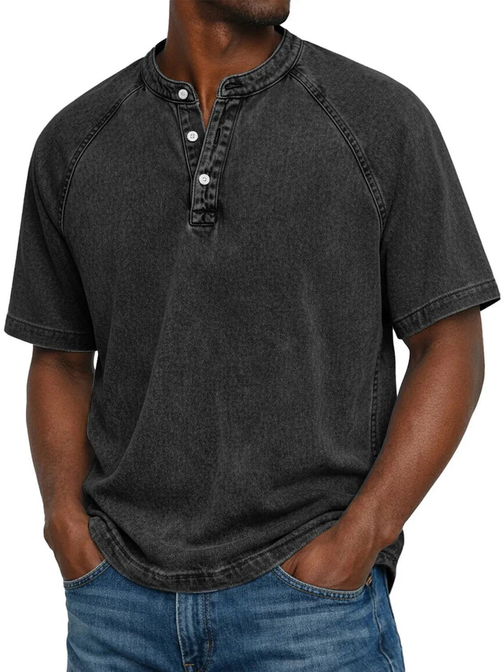 Homme portant le t-shirt Henley lavé noir délavé à manches raglan, col boutonné, mains dans les poches d'un jean. 5