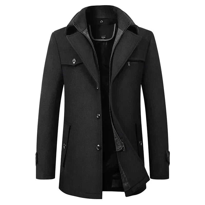 Vue de face du manteau noir boutonné, col tailleur et couche intérieure zippée entrouverte, poche zippée sur la poitrine. 1
