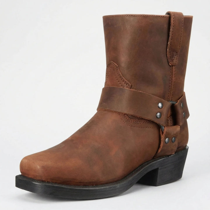 Botte en cuir marron vieilli, vue de trois quarts, avec sangle à anneau, rivets métalliques et talon noir. 2