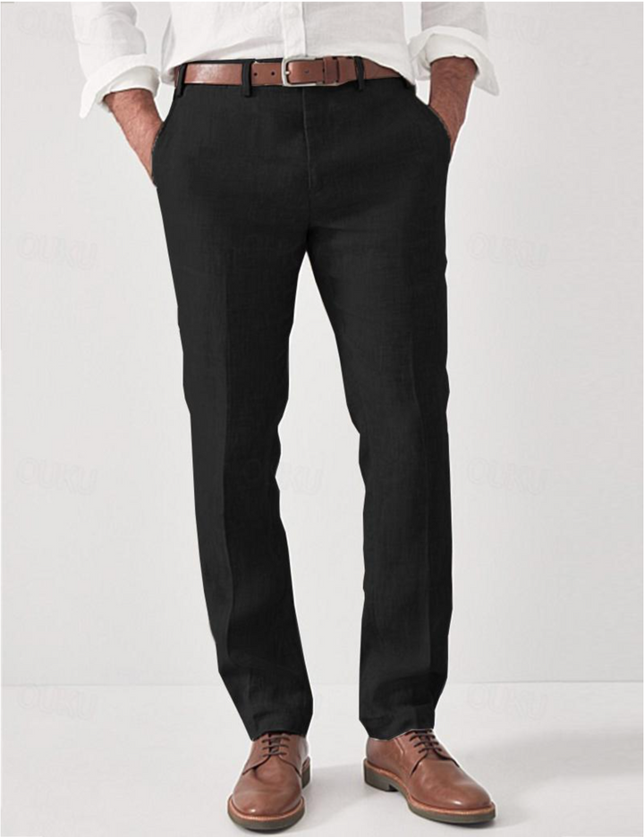 Pantalon en lin noir porté de face avec chemise blanche, ceinture en cuir marron et derbies marron, mains dans les poches. 3