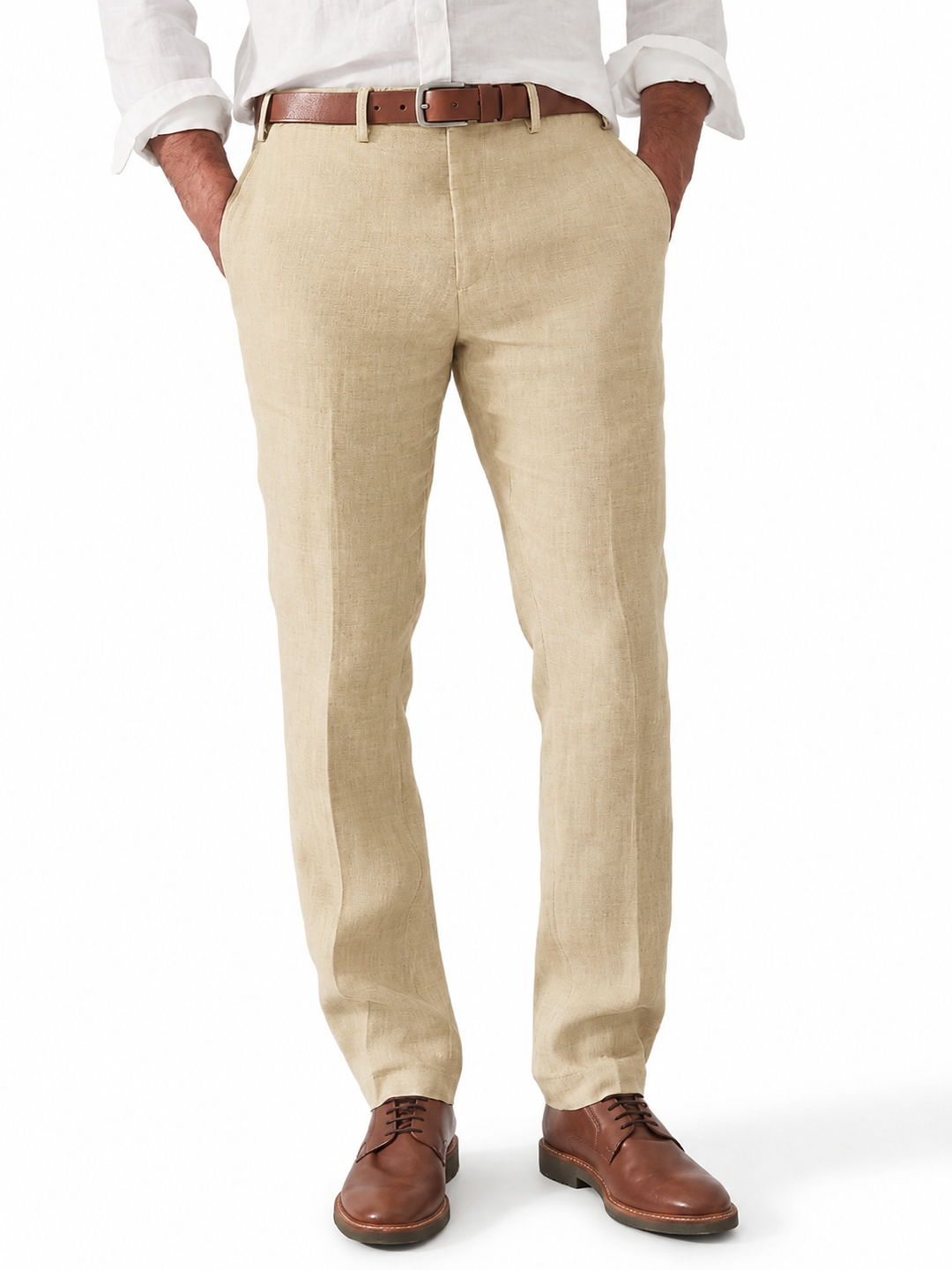 Homme portant le pantalon en lin beige avec chemise blanche, ceinture en cuir marron et chaussures derby, mains dans les poches. 1