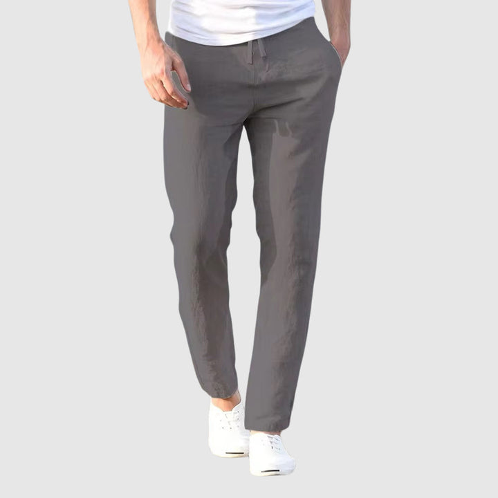 Vue de face du pantalon gris foncé porté par un modèle en t-shirt blanc, cordon de serrage noué à la taille. 3