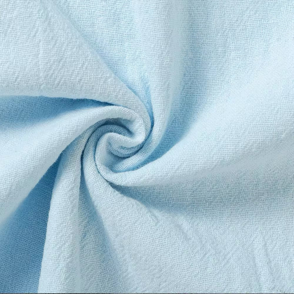 Gros plan sur le tissu bleu ciel torsadé en spirale, montrant la trame fine et l'aspect naturellement froissé du lin. 8