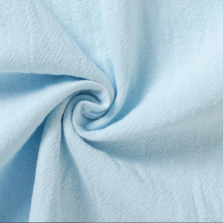 Gros plan sur le tissu bleu ciel torsadé en spirale, montrant la trame fine et l'aspect naturellement froissé du lin. 8