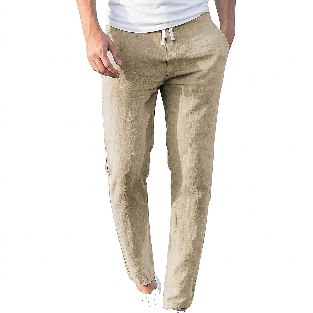 Homme en t-shirt blanc et baskets blanches portant le pantalon beige en lin froissé, cordon noué à la taille, main dans la poche. 1