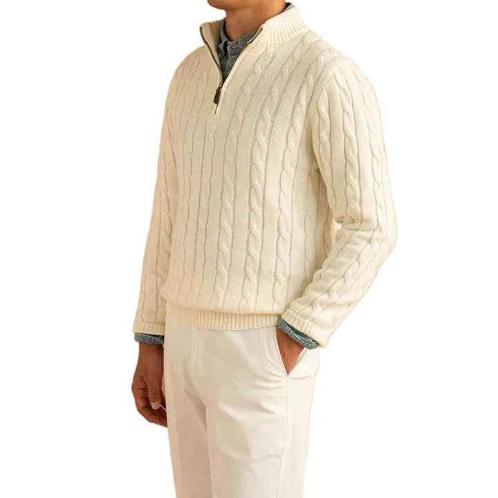 Homme portant le pull crème en maille torsadée avec un pantalon clair, vu de trois quarts, col montant zippé et chemise bleue dessous. 1