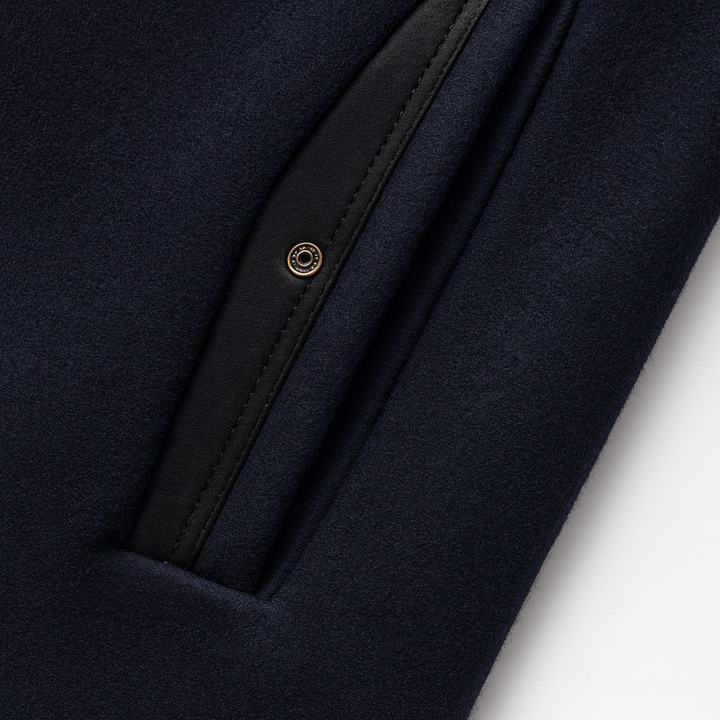 Gros plan sur une poche latérale en laine bleu marine bordée de noir, avec un petit bouton-pression 9