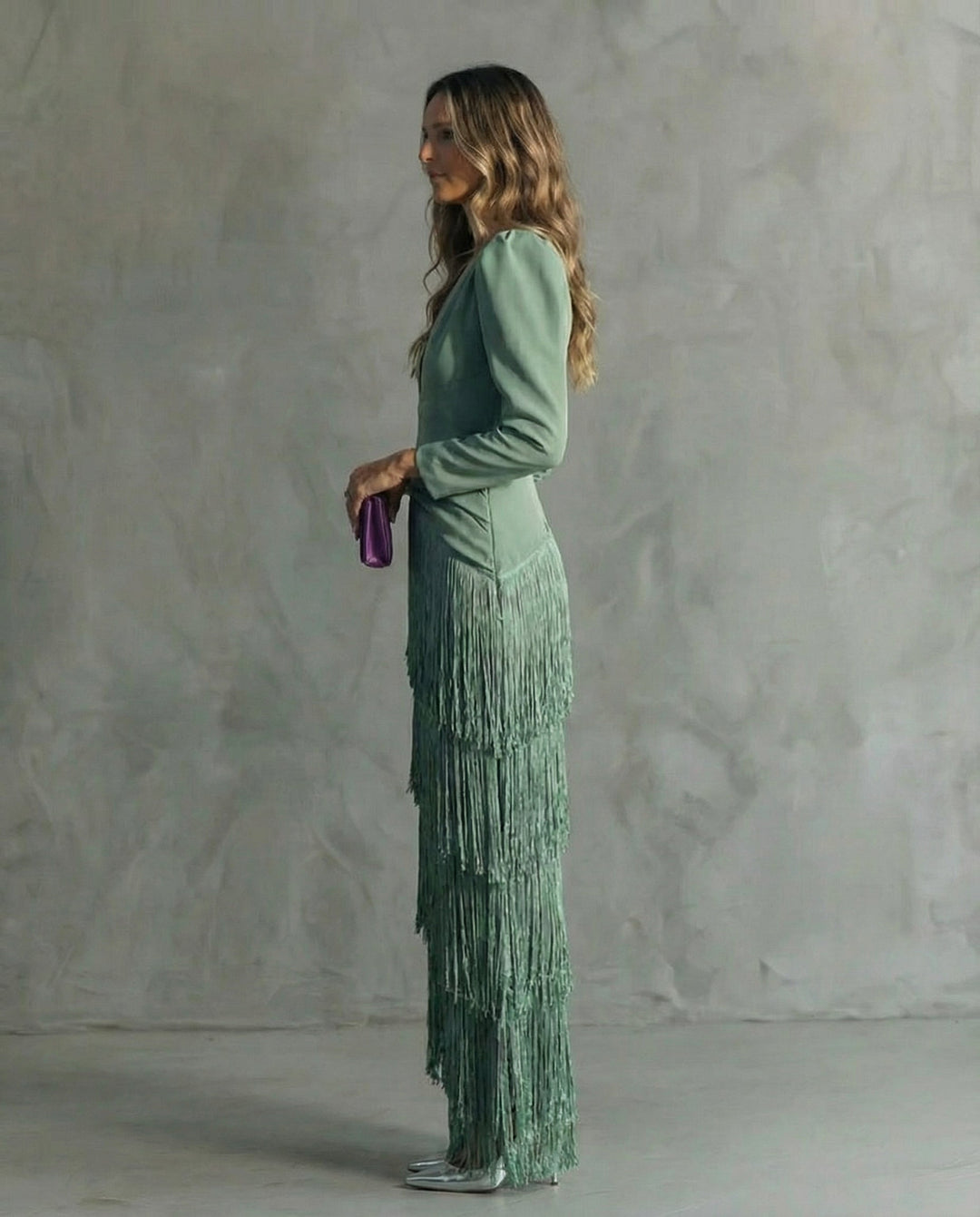 Robe verte à franges étagées vue de profil, manches longues et pochette violette en main 3