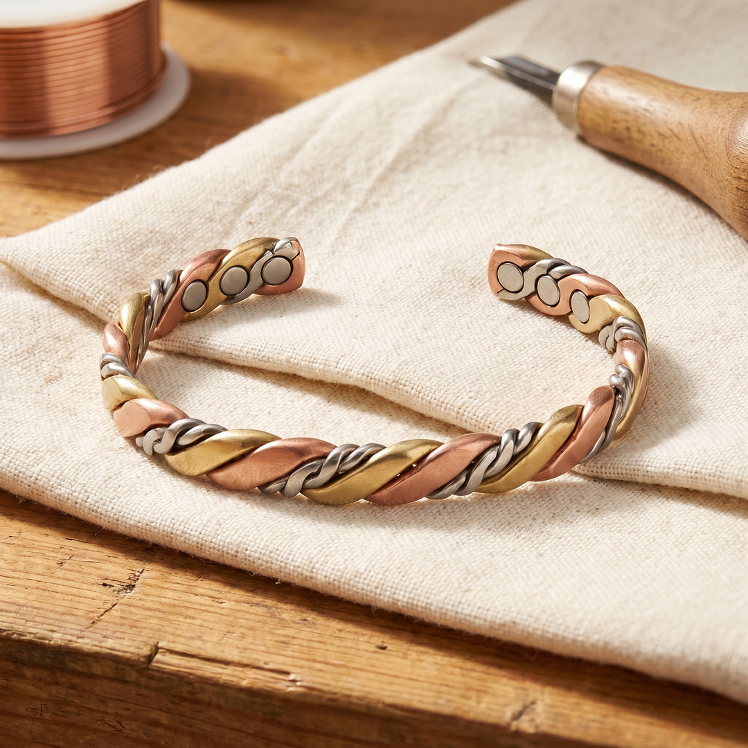 Bracelet ouvert aux brins torsadés cuivre, laiton et argenté, posé sur un lin écru près d'une bobine de fil 1