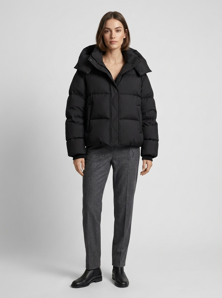 Femme en pied portant la doudoune noire avec pantalon gris et bottines noires, capuche rabattue 4