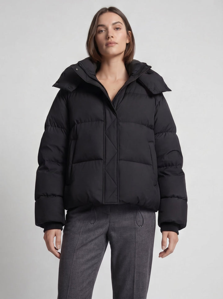 Mannequin de face en doudoune noire fermée, pantalon gris, cordons de serrage visibles à la taille 6