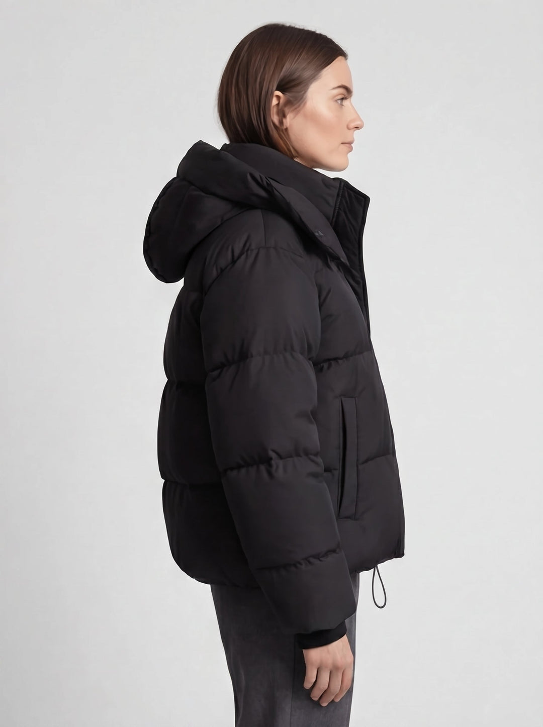 Vue de profil de la doudoune noire portée par une mannequin, capuche relevée, poche zippée visible 5