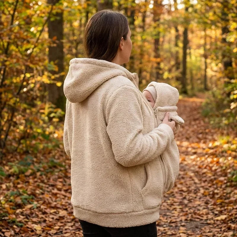 Femme de dos et de profil en sweat beige à capuche, bébé blotti dans l'empiècement, sur un chemin de forêt automnale. 12