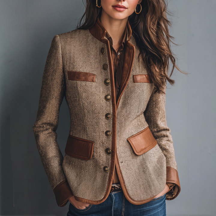 Veste ajustée en tweed à chevrons portée par une mannequin avec chemisier brun et jean, boutons métalliques et poches à rabat marron. 1