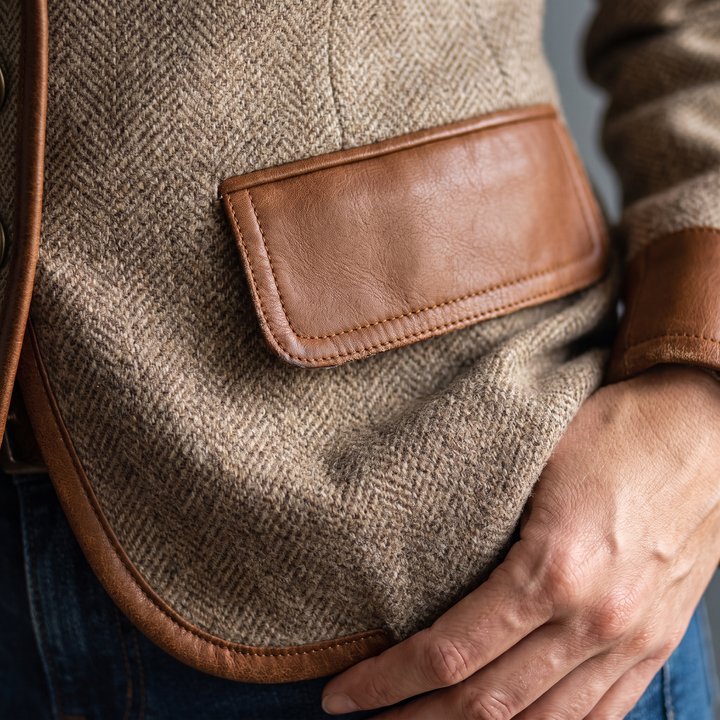 Détail d'une poche à rabat en simili-cuir surpiqué sur tweed à chevrons, avec bordure de l'ourlet et poignet en simili-cuir. 5