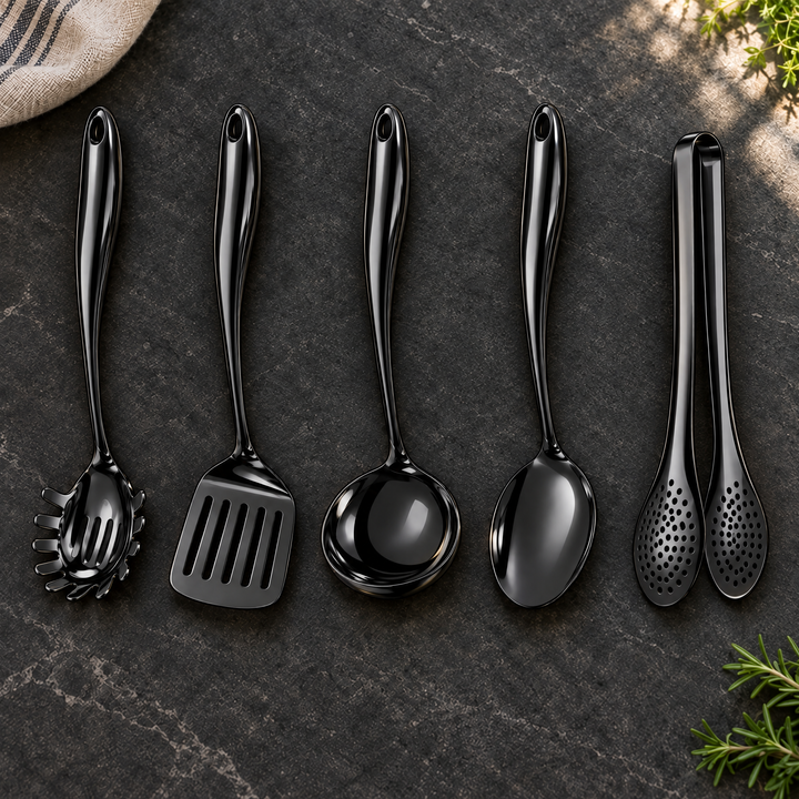 Cinq ustensiles noirs alignés sur une pierre sombre : cuillère à spaghettis, spatule ajourée, louche, cuillère et pince, avec torchon et herbes. 28