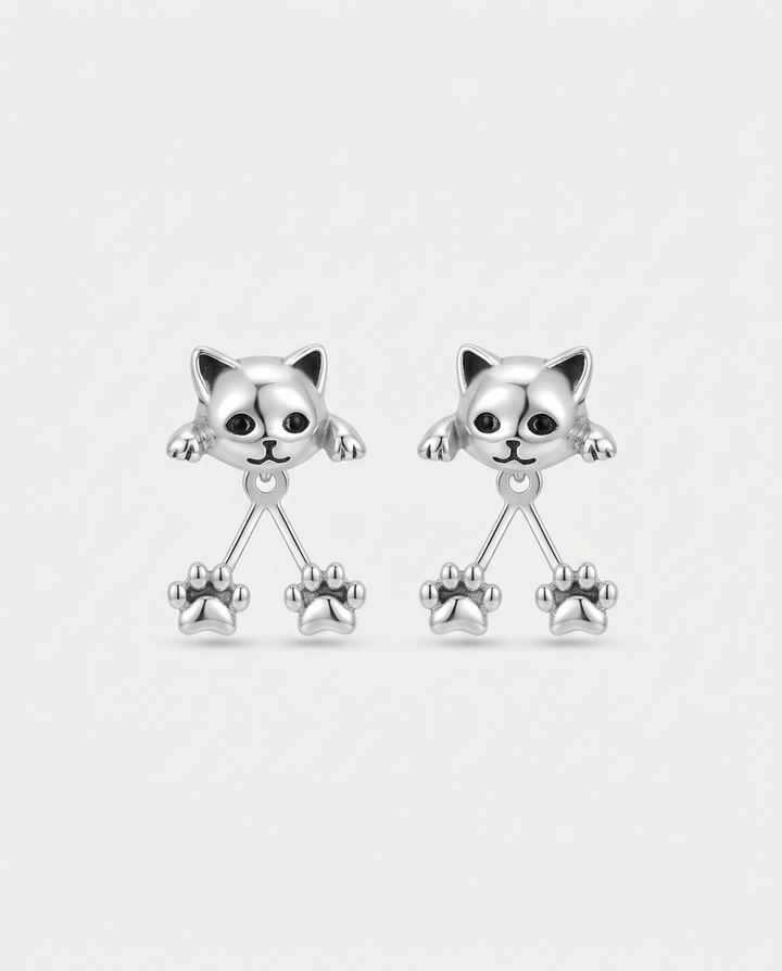 Paire de boucles d'oreilles argentées, têtes de chat aux yeux noirs et deux pattes pendantes, sur fond blanc 1