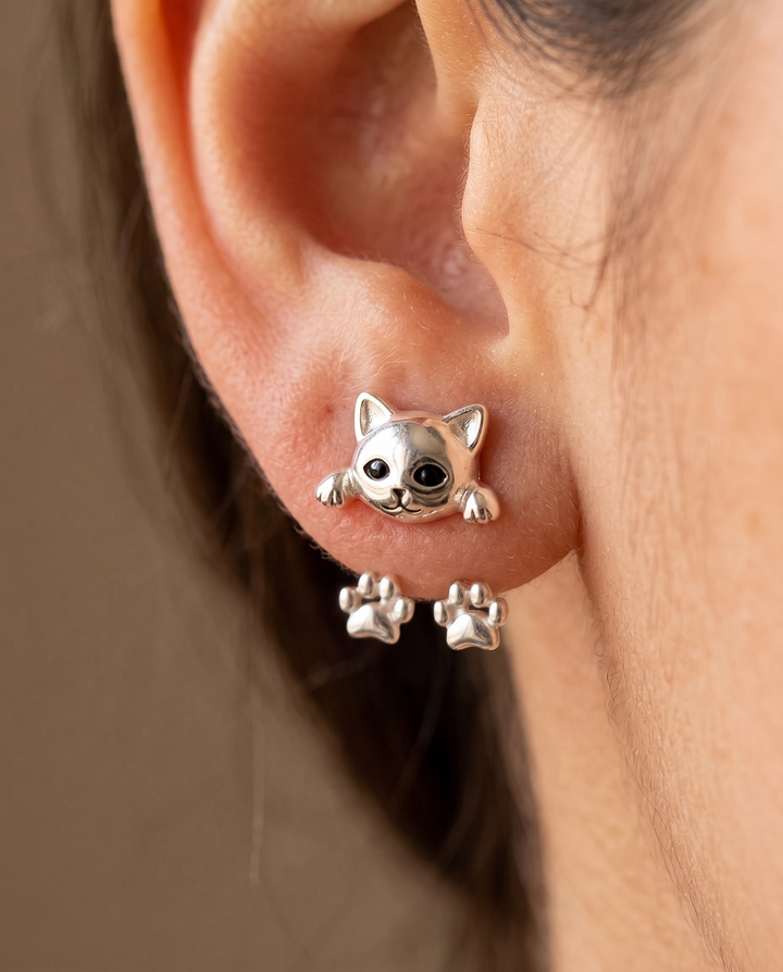 Gros plan sur une boucle portée à l'oreille: tête de chat sur le lobe, pattes dessous 3