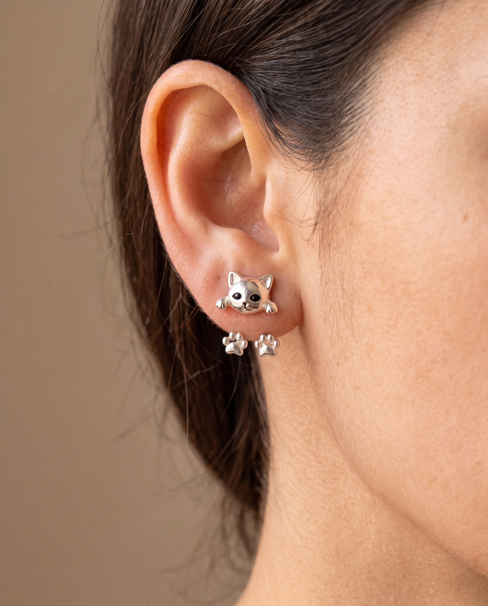 Oreille d'une femme portant la boucle en tête de chat, avec les deux pattes visibles derrière le lobe 2