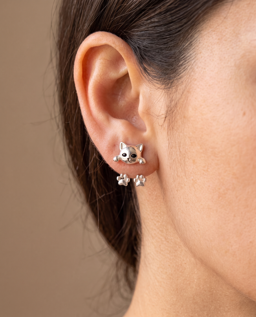 Oreille d'une femme portant la boucle en tête de chat, avec les deux pattes visibles derrière le lobe 2