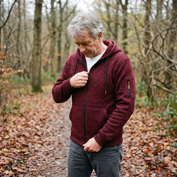 Homme aux cheveux gris portant le sweat bordeaux sur un tee-shirt blanc, en forêt, en train de remonter la fermeture éclair. 6