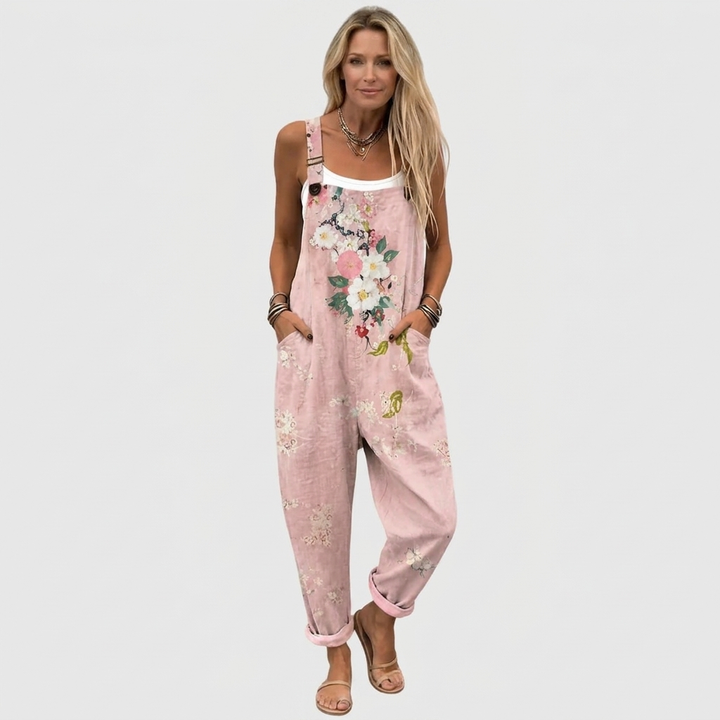 Femme blonde en pied, de face, portant la salopette rose à fleurs sur un débardeur blanc, avec des sandales. 2
