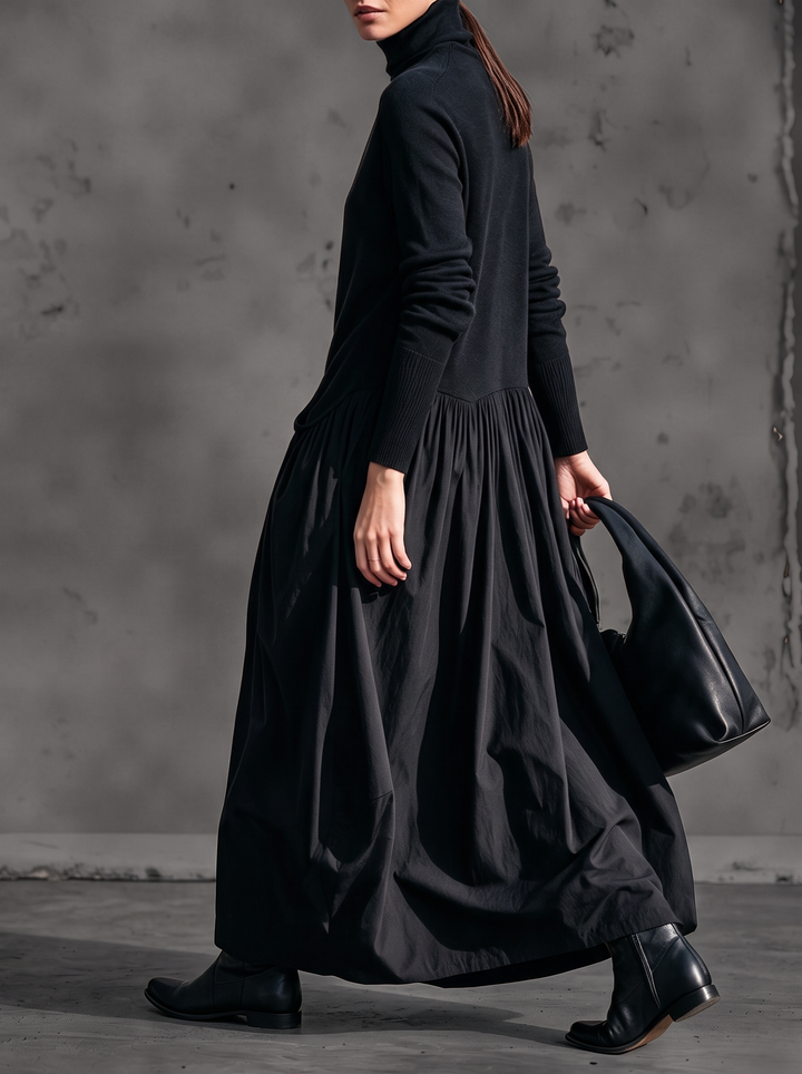 Mannequin en marche vue de trois quarts, robe noire ample à jupe froncée, bottines et sac 2