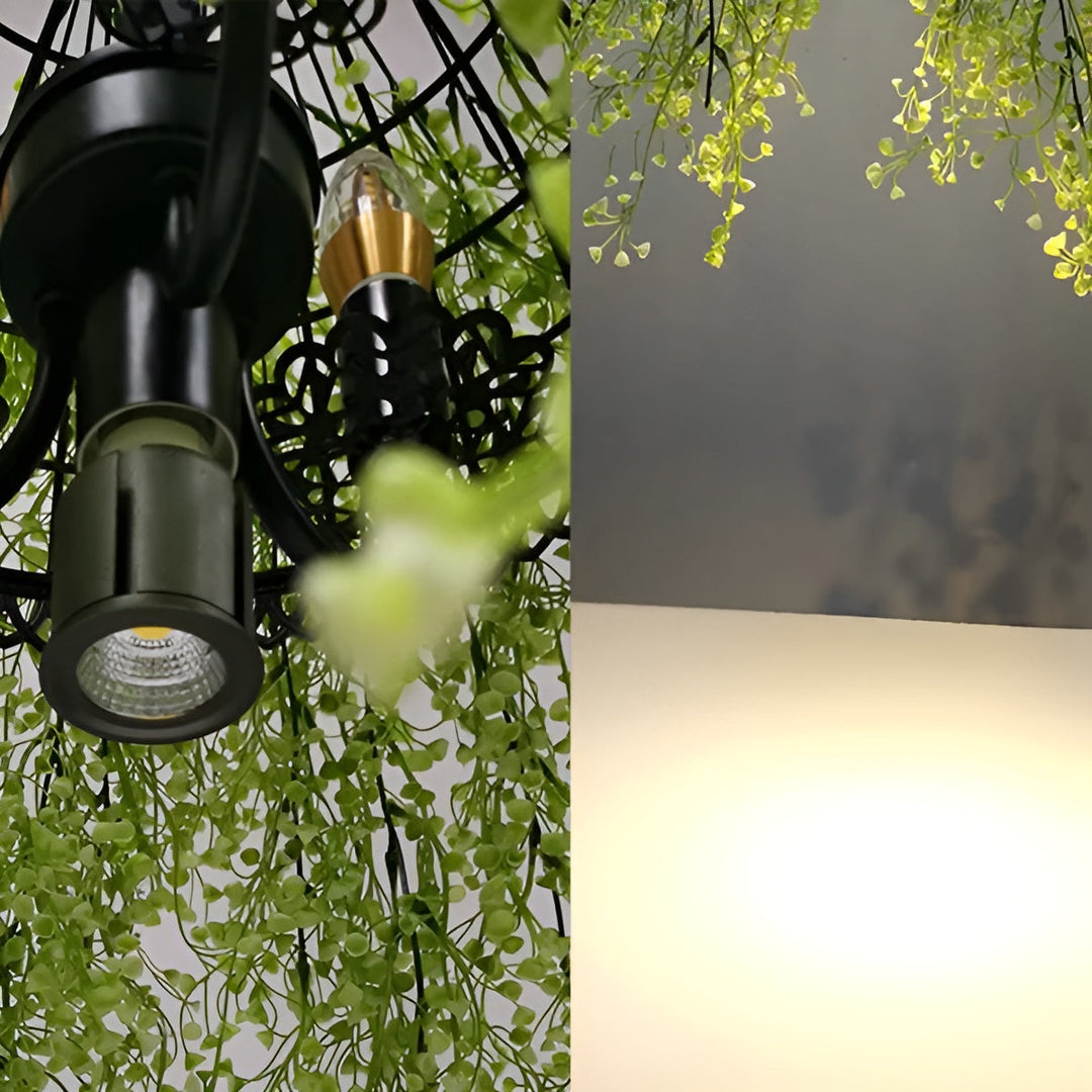 Gros plan sur les ampoules et le spot noir de la structure en métal, entourés de verdure 9
