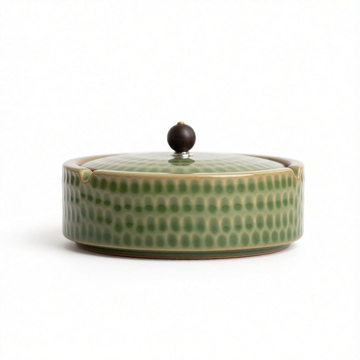 Cendrier de profil, version vert clair craquelé à motif martelé, avec couvercle et petite poignée ronde brun foncé, fond blanc. 7