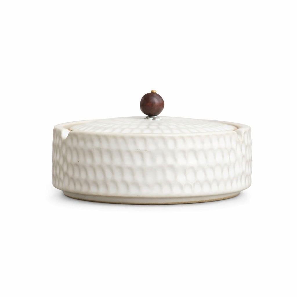 Cendrier de profil, version blanc crème à motif martelé, avec couvercle et poignée ronde en bois brun rougeâtre. 10