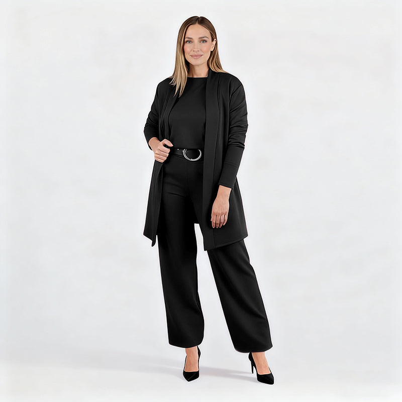 Ensemble noir porté par une mannequin en pied sur fond blanc, cardigan ouvert, ceinture à boucle ronde, escarpins noirs. 15