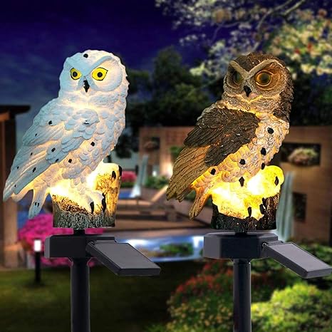 Deux hiboux allumés côte à côte la nuit dans un jardin, l'un blanc aux yeux jaunes, l'autre brun, chacun avec son panneau solaire. 17