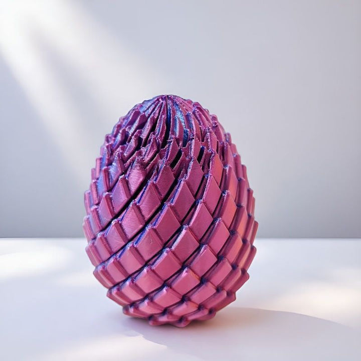 Œuf de dragon à écailles rose violacé posé sur une surface blanche, avec des ombres douces en diagonale. 10