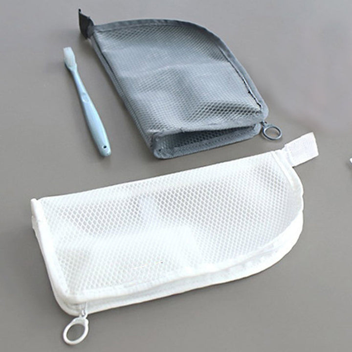 Deux pochettes à plat, une blanche et une grise en filet, avec leur fermeture à anneau, une brosse à dents bleue à côté. 6