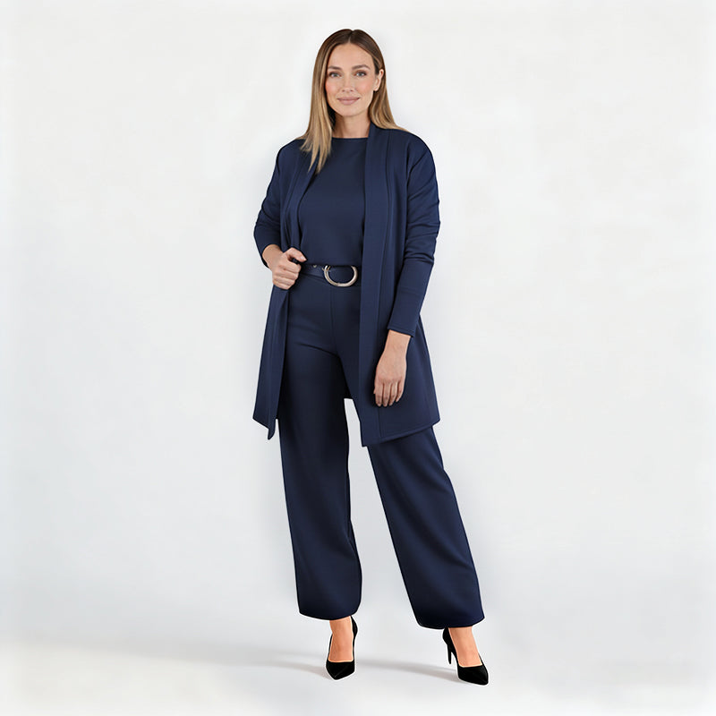 Ensemble bleu marine porté par une mannequin en pied sur fond blanc, cardigan ouvert, ceinture à boucle ronde, escarpins noirs. 12