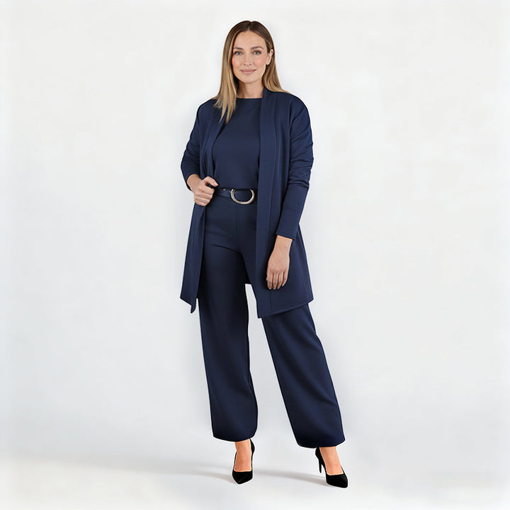 Ensemble bleu marine porté par une mannequin en pied sur fond blanc, cardigan ouvert, ceinture à boucle ronde, escarpins noirs. 12