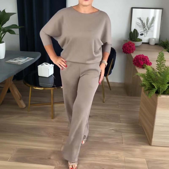 Femme portant le haut taupe à manches chauve-souris et le pantalon large assorti, une main sur la hanche, dans un salon. 8