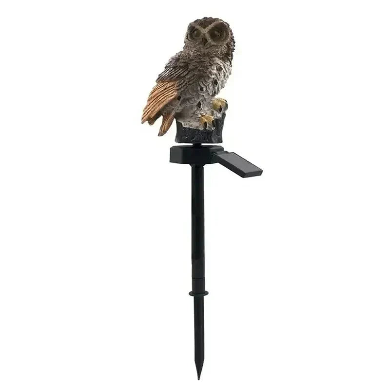 Version brune du hibou, aux ailes orangées, perchée sur sa souche avec piquet noir et panneau solaire, sur fond blanc. 16