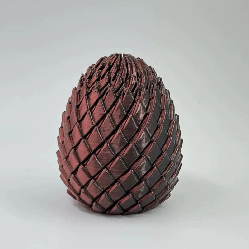 Œuf de dragon à écailles rouge cuivré aux reflets sombres, vu de face sur fond gris clair. 12