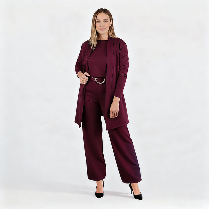 Ensemble bordeaux porté par une mannequin en pied sur fond blanc, cardigan ouvert, ceinture à boucle ronde, escarpins noirs. 13