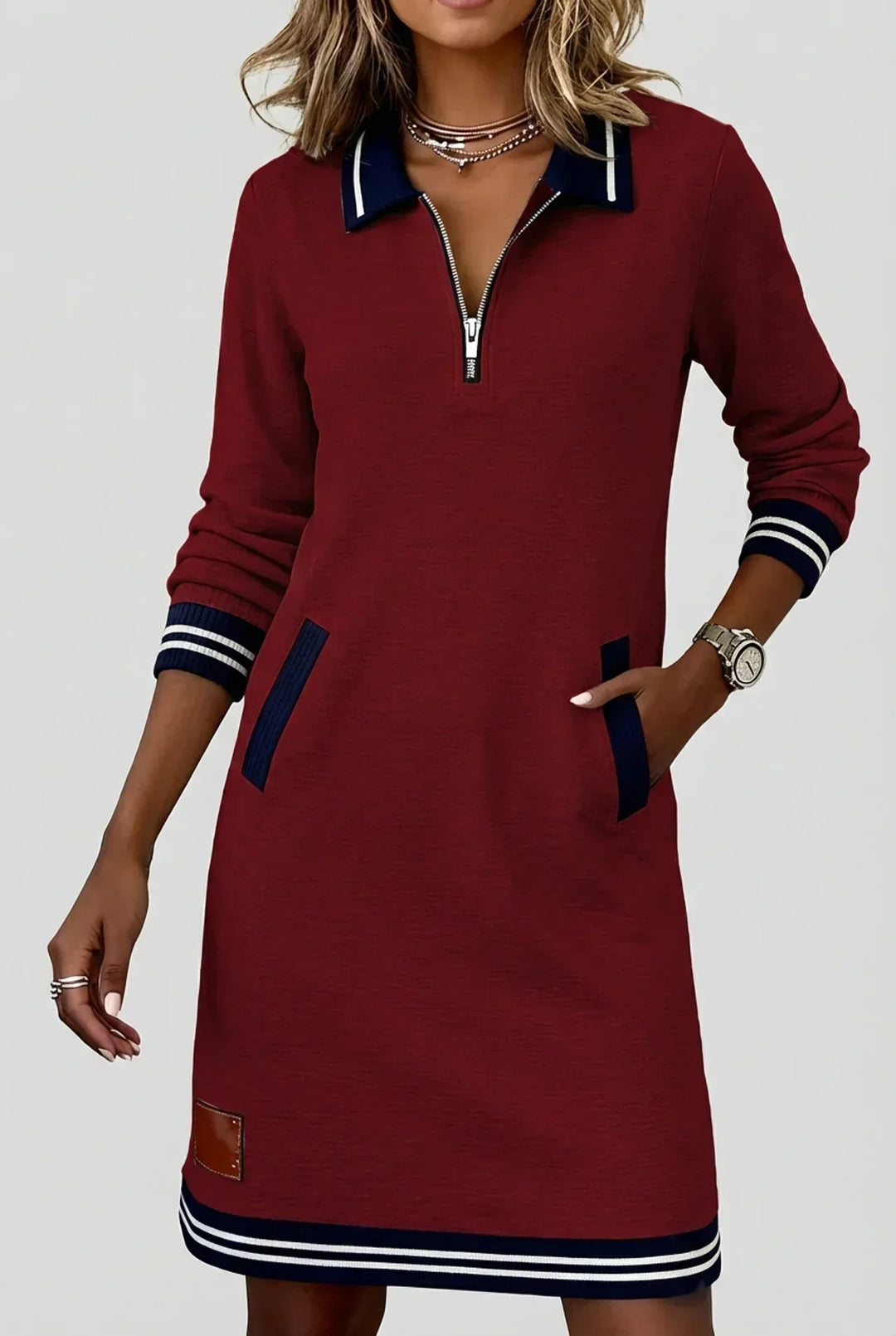 Robe bordeaux à col polo bleu marine, portée par un mannequin la main dans la poche, ourlet rayé. 5