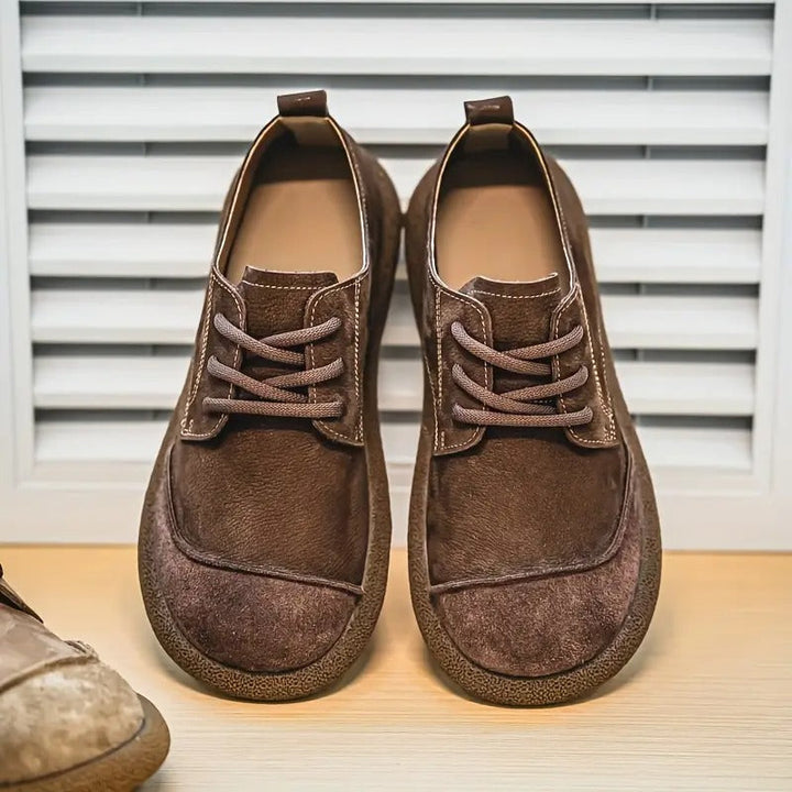 Paire de chaussures à lacets marron foncé en cuir velours, vue de face devant un volet blanc. 10