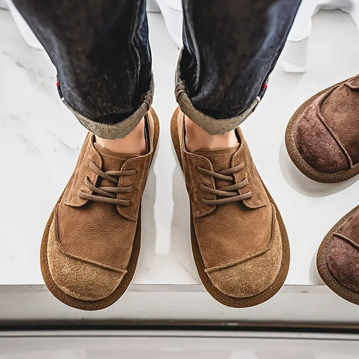 Vue de dessus des chaussures camel portées avec un jean retroussé, deux paires marron visibles à droite. 4