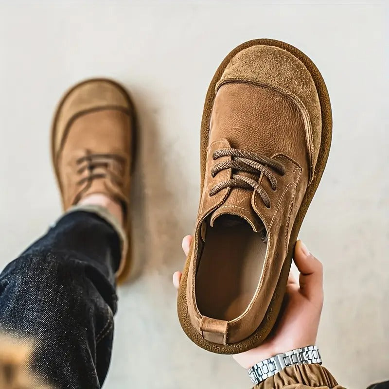 Chaussure beige tenue en main au premier plan, vue d'en haut, montrant l'intérieur doublé et le bout renforcé, l'autre chaussure portée. 5