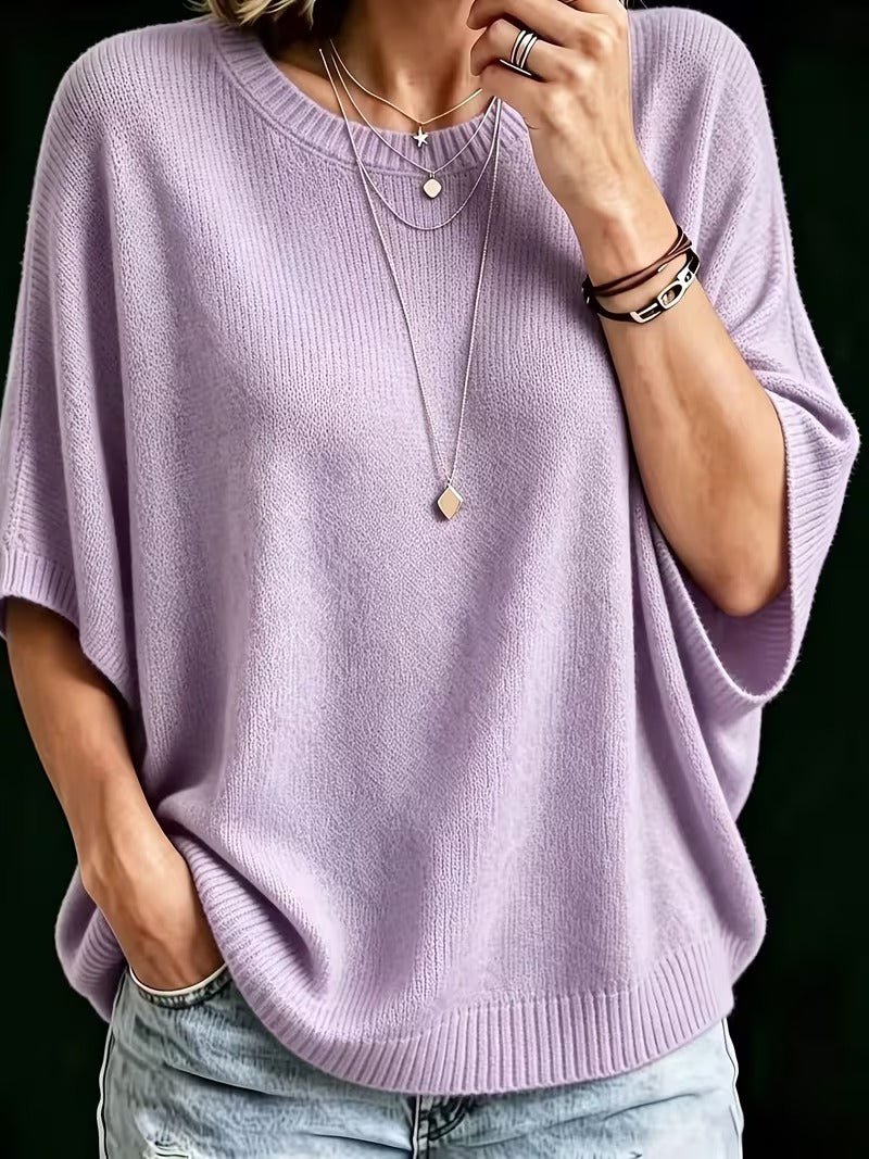 Top en maille lilas, plan rapproché de face, main au col, manches amples côtelées, colliers fins et bracelets. 7