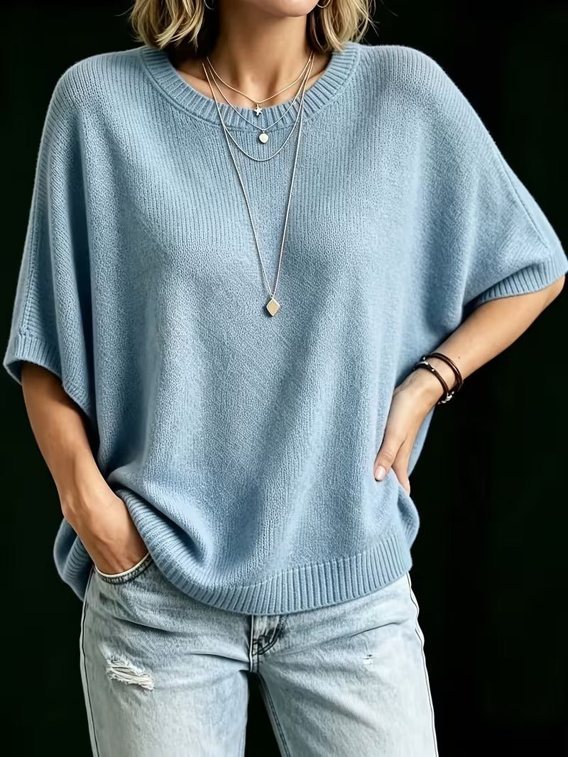 Top bleu clair porté, une main dans la poche du jean et l'autre sur la hanche, manches amples. 15