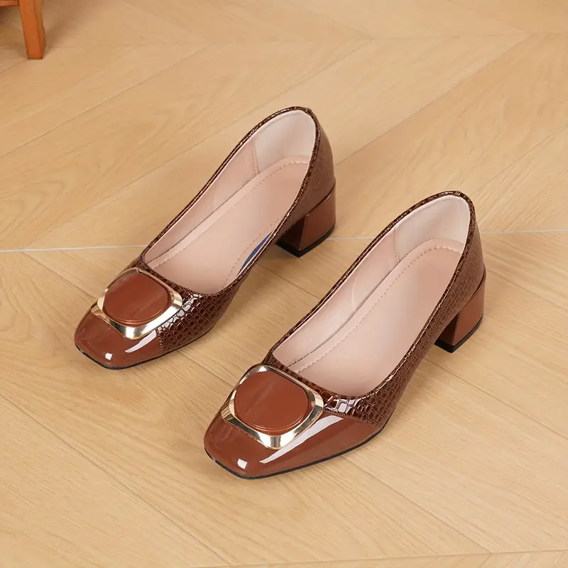 Paire d'escarpins marron posée sur un parquet, vue du dessus montrant l'intérieur doublé de beige clair et la boucle dorée. 4