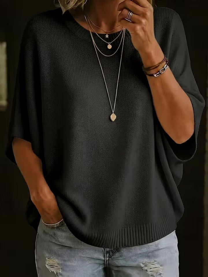 Gros plan sur le top en maille noir porté de face avec plusieurs colliers fins et des bracelets. 26