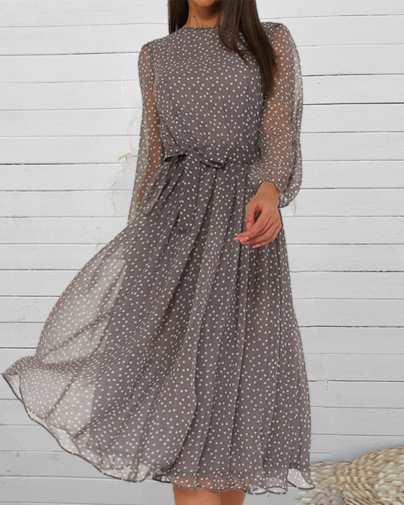 Robe grise à pois blancs en voile fluide portée par un mannequin devant un mur de lattes blanches, corbeille en osier. 2