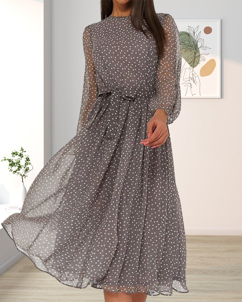 Robe grise à pois blancs et manches transparentes portée dans un salon clair, avec plante verte et tableau au mur. 4